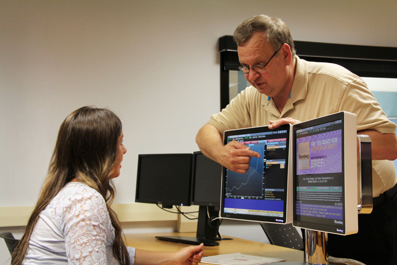 Dr. Alex Faseruk instructs a student at a Bloomberg terminal at the Faculty of Business Administration. A similar terminal is being installed in Memorial’s university library.